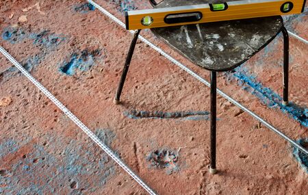 Installation of a guide for the concrete screed. Level tool on chair. Preparing to fill the floor. Home renovation.の写真素材