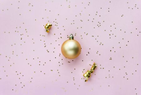 Christmas sparkles composition. Christmas ball and golden stars on pastel pink background.の写真素材