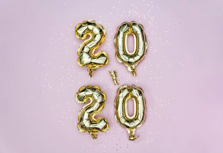 Vertical 2020 Happy New year celebration. Gold foil balloons numeral 2020 and golden stars on pastel...