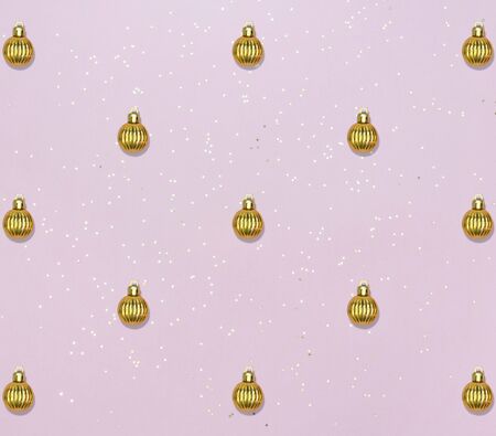 Holiday pattern with golden balls and star confetti on pink pastel background. Christmas or New year...