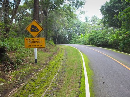 Use low gear and steep grade warning signs beside a downhill sharp curve in Chiang Mai,Thailand. Horizontal shotの写真素材