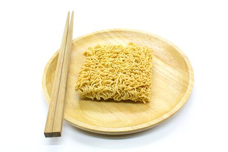 Famous dried instant noodles and chopsticks isolated on a wooden plate with white background. Horizontal shot.の写真素材