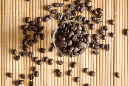 A cup of coffee beans on bamboo matの写真素材
