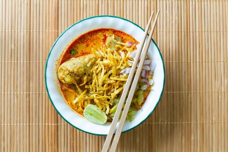 Northern Thai food (Khao Soi), spicy curry noodles soup with coconut milk and chicken on bamboo mat, Top viewの写真素材