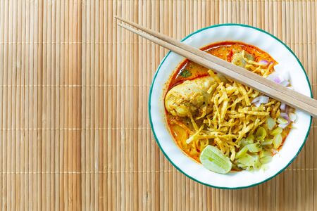 Northern Thai food (Khao Soi), spicy curry noodles soup with coconut milk and chicken on bamboo mat, Top viewの写真素材