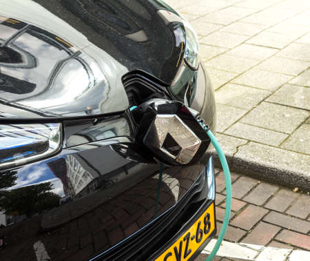 ROTTERDAM, NETHERLANDS : EV Car or Electric car at charging station with the power cable supply plugged in on blurred nature with soft light background. Eco-friendly alternative energy conのeditorial素材