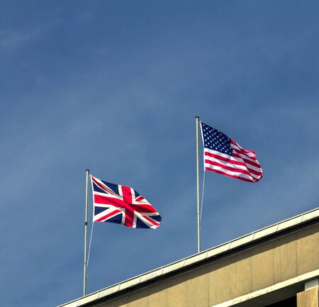 USA and UK flags in the blue sky / English and American flag waving - U.S.A. and UK