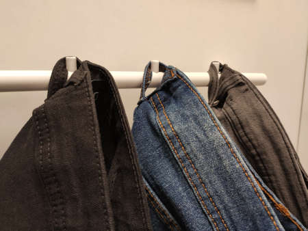 Three pairs of jeans trousers hanging on a hamgerの写真素材
