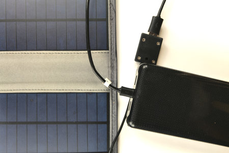 A big black power bank is being charged from a portable solar panel on a white backgroundの写真素材