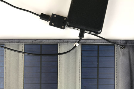 A big black power bank is being charged from a portable solar panel on a white backgroundの写真素材