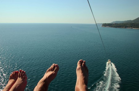 A pair of legs in flight over the sea with a parachuteの写真素材