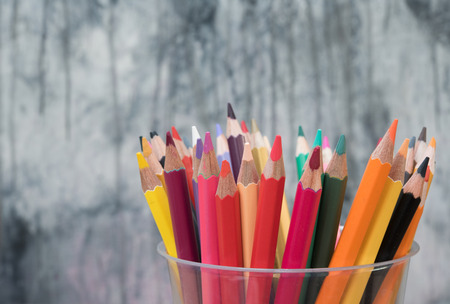 Pens and pencils in a glass in front of wall backgroundの写真素材