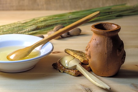 two wooden spoons, cookies and a ceramic plate next to a clay pot on a wooden tableの写真素材