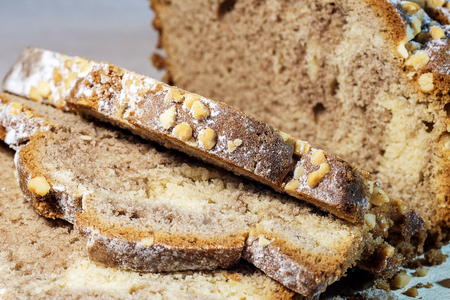Freshly baked homemade cake, decorated on top with powdered sugar, cut into slices, on a wooden...
