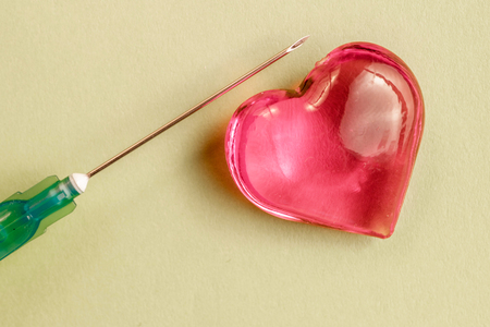 glass heart on colored paper which extends the game a medical syringe, heartの写真素材