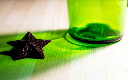 the bottle casts a shadow on a star which lies on a wooden table, alcoholism stars allegory, areaの写真素材