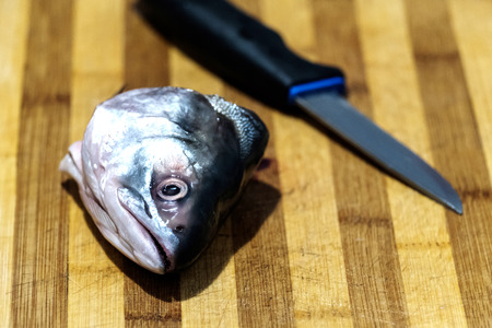 process of cutting fish, cut fish head on a wooden board, knife and fishの写真素材
