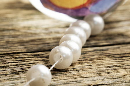 homemade needlework collecting necklaces from white beads on a string, wooden tableの写真素材