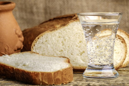 sliced white bread and a glass of vodka on a wooden tableの写真素材