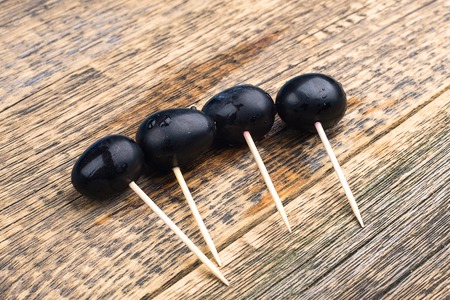 Dark berries lie on a wooden table on wooden skewersの写真素材