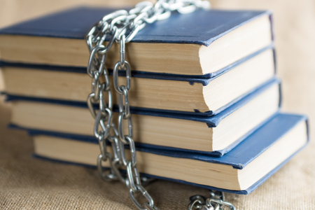 close-up of books that are wrapped in a metal chain lying on burlapの写真素材