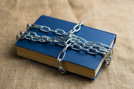 top view of a book in a blue cover lying on burlap, the book is wrapped in a chain, a forbiddenの写真素材