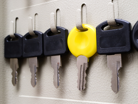 yellow key among the black keys hanging in a row on metalの写真素材