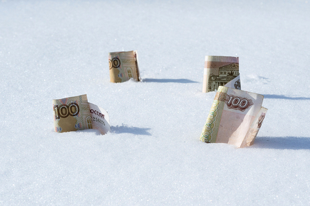 denominations of 100 rubles inserted in the snow, frozen rublesの写真素材