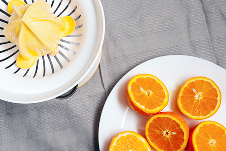 a juicer and chopped oranges in two, a top view of a fabric backgroundの写真素材