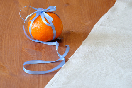 divided into half, a torn fabric background and a wooden, an orange in a blue ribbon tied in a bowの写真素材