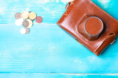 old camera in a brown leather cover on a wooden table, next to the moneyの写真素材