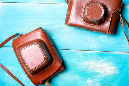 two old cameras in leather brown covers, the camera is on a wooden table in blueの写真素材