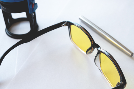 metallic stylish fountain pen next to yellow glasses and print, white backgroundの写真素材