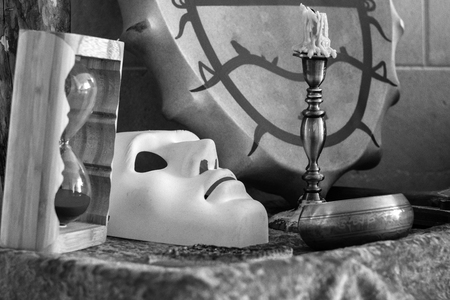 black and white photograph theater mask lies on the background of a semicircle next to an hourglassの写真素材