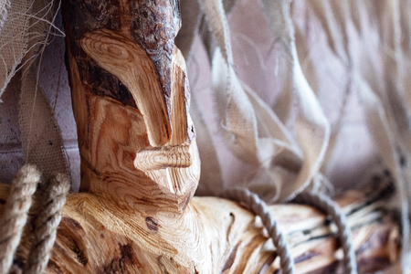 a wooden shaman idol that looks like a human face tied with ropes, a background of crumpled clothの写真素材