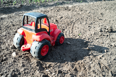 on the field from the soil is a red tractor, rear viewの写真素材