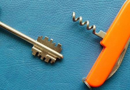 old rusty key and penknife with a corkscrew for opening bottles, blue background of unnatural...