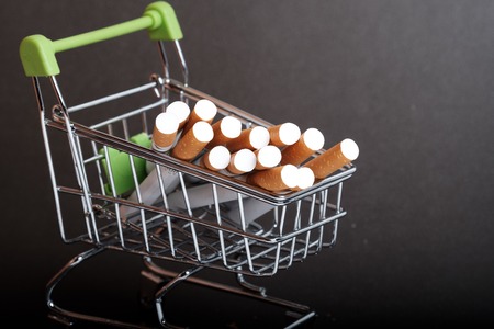 lots of cigarettes stacked in shopping basket filters to us, buying cigarettes wholesale, dark backgroundの写真素材