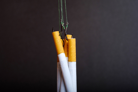 tangled strands with hooks on which hang the cigarettes, don't get caught on the hook of nicotine, black backgroundの写真素材