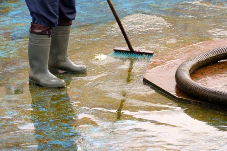 man in boots cleans after the summer season the bottom of the fountain, brush and pumpの写真素材