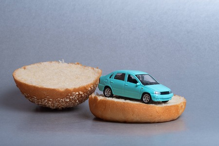 blue car on a bun from the Burger, bread and a toy carの写真素材