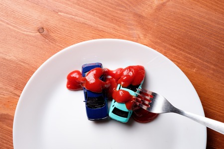 toy cars bathed in red sauce are in the dish is white, next is the fork made of stainless steel, the...