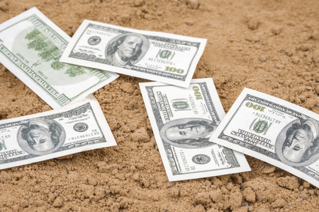 dollars lying on the sand, yellow sand and paper moneyの写真素材