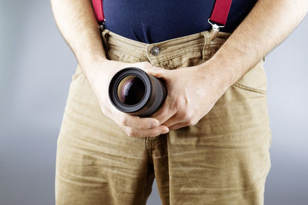 the man sticks out the lens of his pants, a large lens and yellow pants on a gray backgroundの写真素材