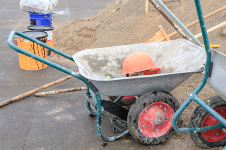 construction materials and a wheelbarrow with a helmet on a dark surface, preparation for construction.の写真素材