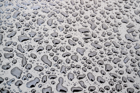 rain drops of various shapes on the bitumen the black surface under the open sky, the shape of water
