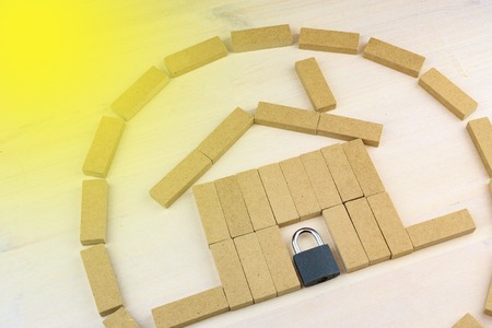 the house is assembled from bars with a yellow light in the upper left corner, padlock where the doors should beの写真素材