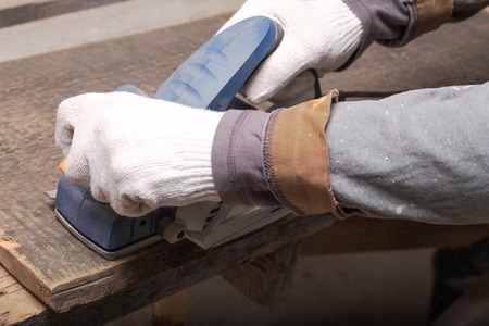worker electric tool on wood, hands in white gloves natural working conditions, home masterの写真素材