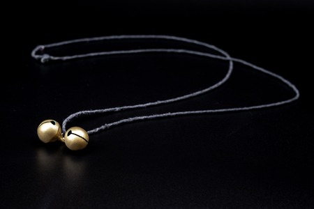 two bells on a string lie on a black background, copper bells for wearing on the neckの写真素材