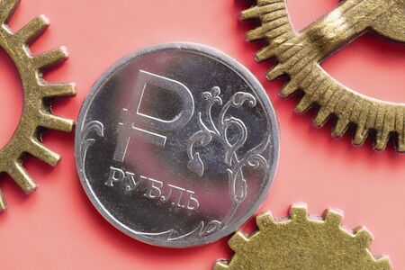 Russian ruble one coin on a pink background in contact with the gears of bronze. built-in mechanical system rubleの写真素材